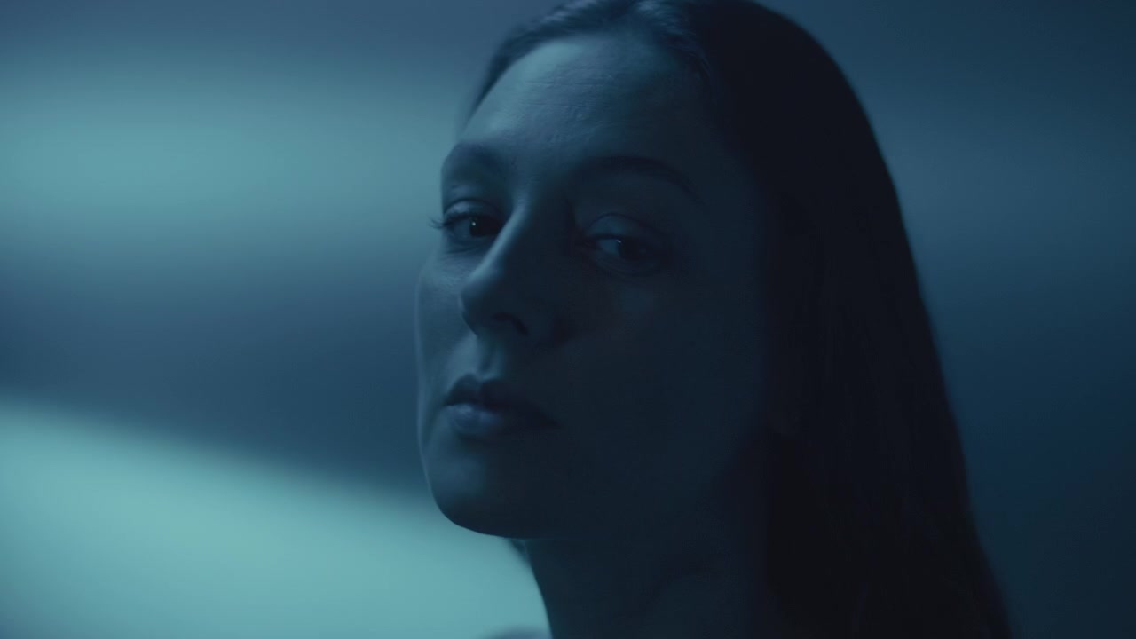 Contemplative Woman Looking Up in Blue Neon Light, then Turning to Camera