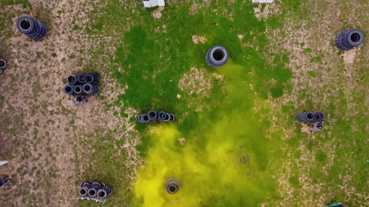 bengala de humo activada en un campo de batalla de paintball con jugadores jugando un tiro de dron de partido