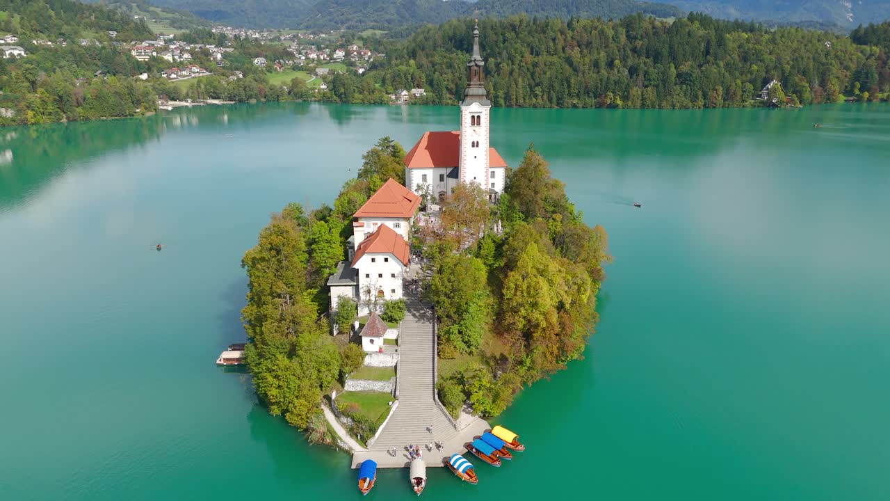 Aerea: isola di Bled e Chiesa dell'Assunzione di Santa Maria di giorno a Bled, Slovenia, ripresa a drone con effetto parallasse