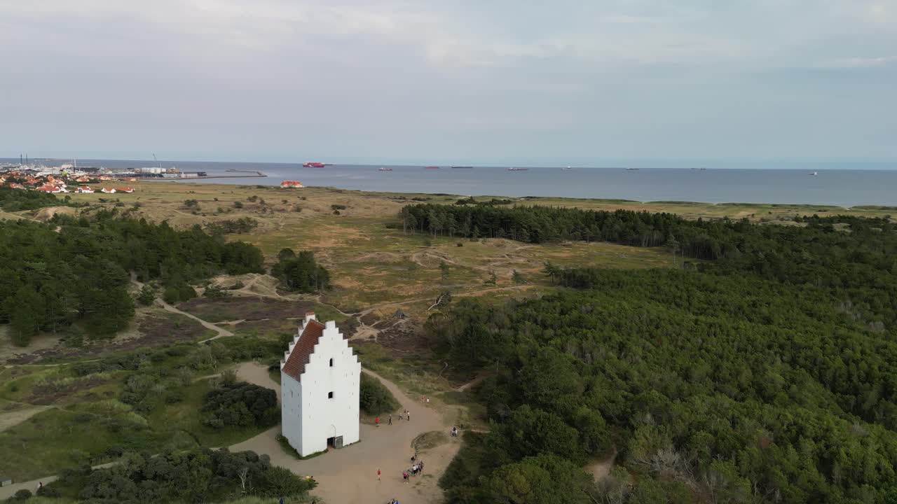 órbita aérea de la iglesia den tilsandede y la ciudad y los pastizales de skagen, dinamarca