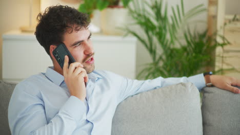 Man-Sits-on-Sofa-and-Talks-on-Cell-Phone