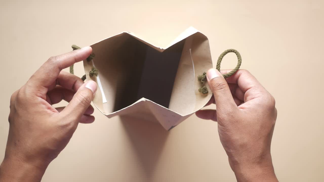 두 손 은 열린 갈색 종이 선물 가방 을 들고 있다