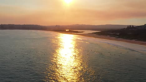 beautiful sunset on coastline tropical beach with golden sea and surfers silhouette on ocean travel people on orange nature background sydney australia