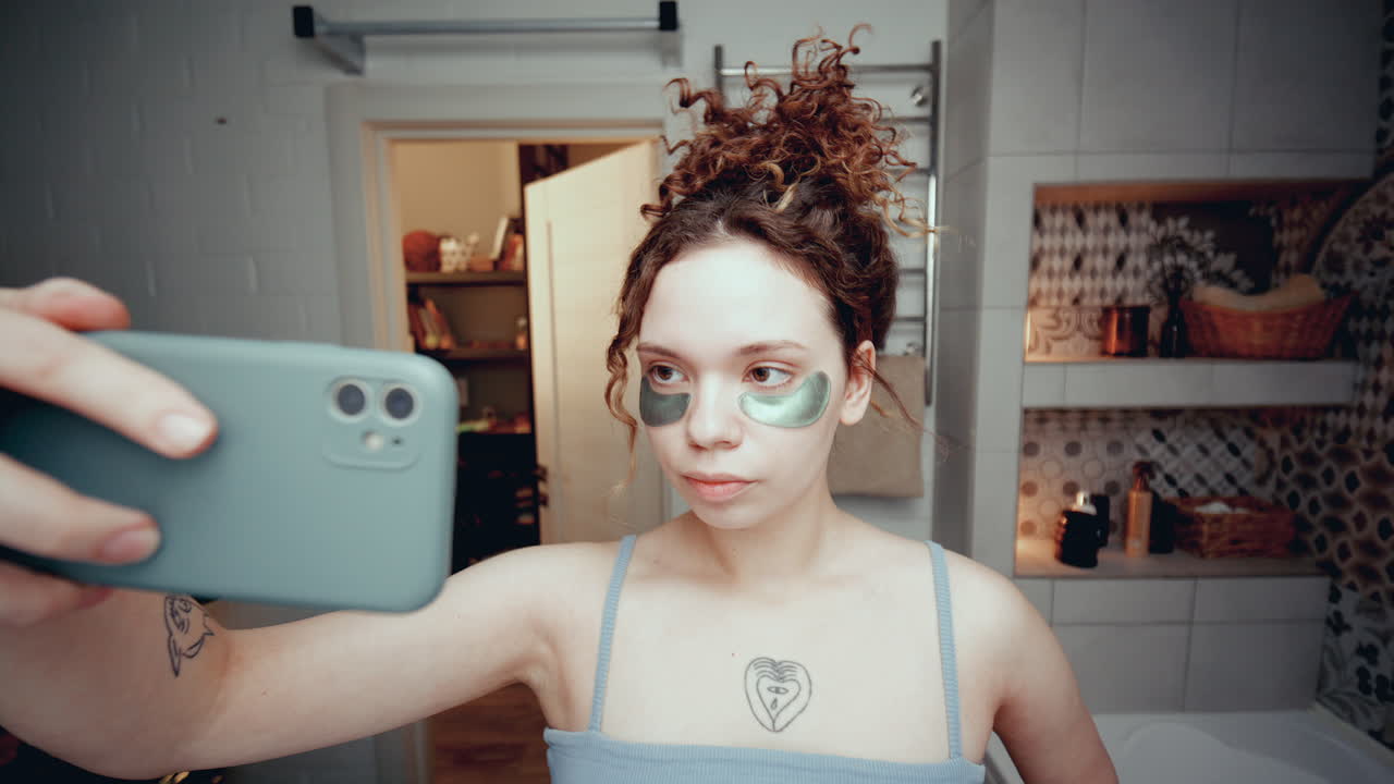 blogger de belleza con parches debajo de los ojos tomando selfies con el teléfono en el baño