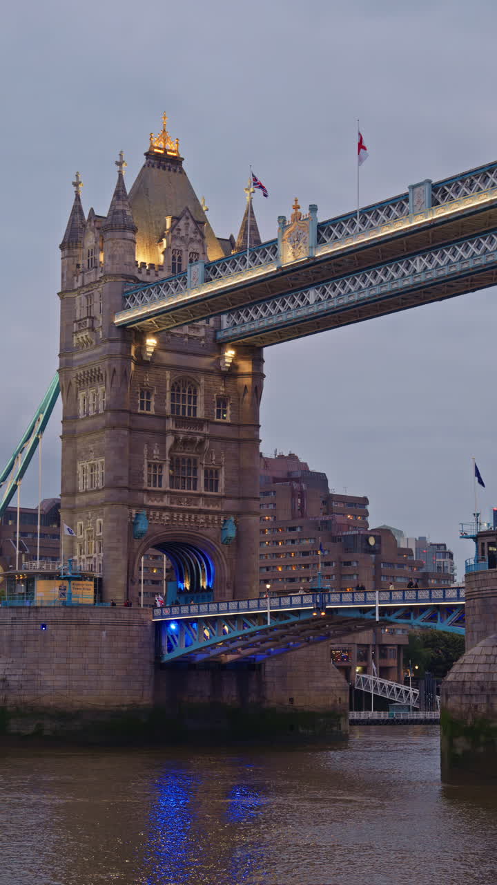 Close-up da Tower Bridge com pessoas caminhando na ponte e suas torres icônicas iluminadas em azul em Londres, Inglaterra. Vertical