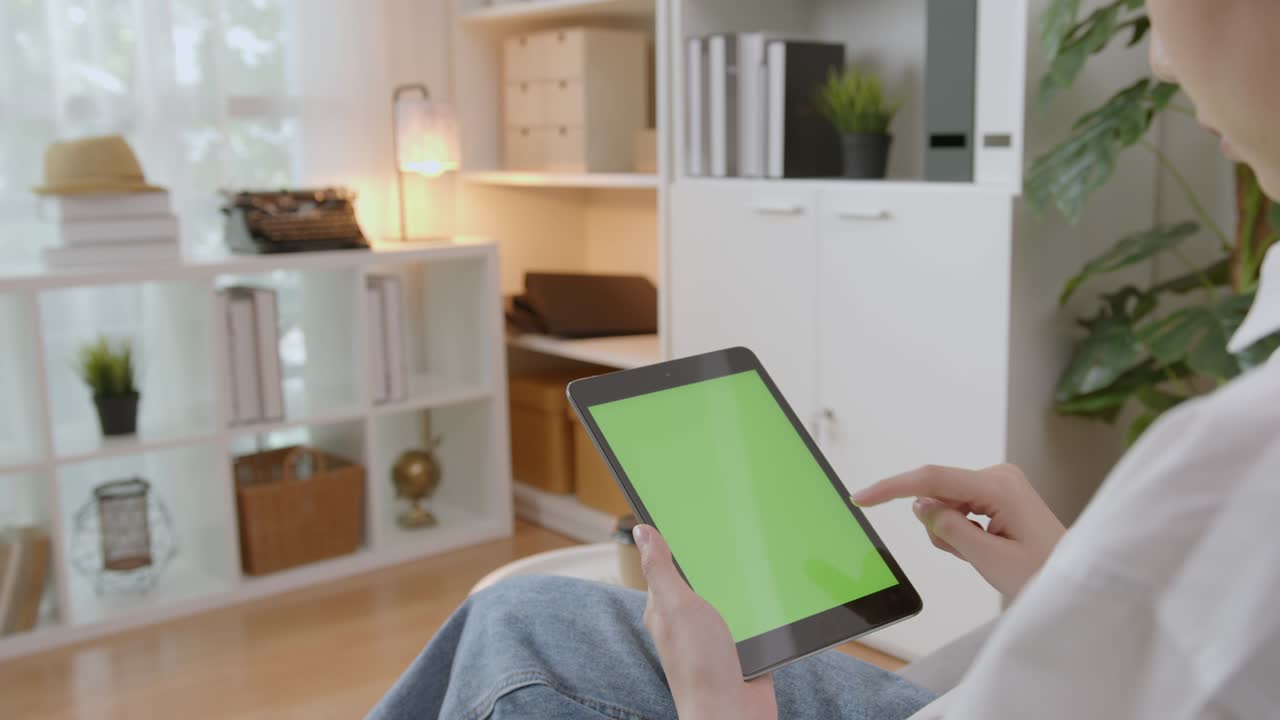 mujer sosteniendo una tableta digital con pantalla verde y dispositivo táctil navegando por internet.