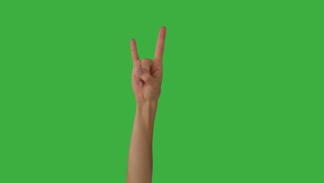 woman giving rock hand sign over green screen