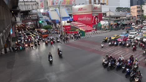 motorcycles and cars navigating a crowded crossroad.