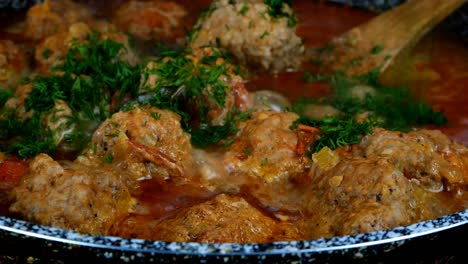 cooking delicious meatballs in creamy tomato sauce in frying pan. small round cutlets filled with spicy sauce.