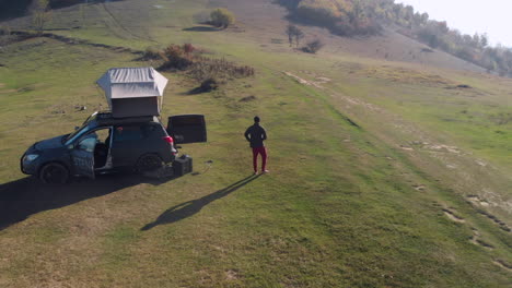 young male enjoys his morning at his car with rooftoptent