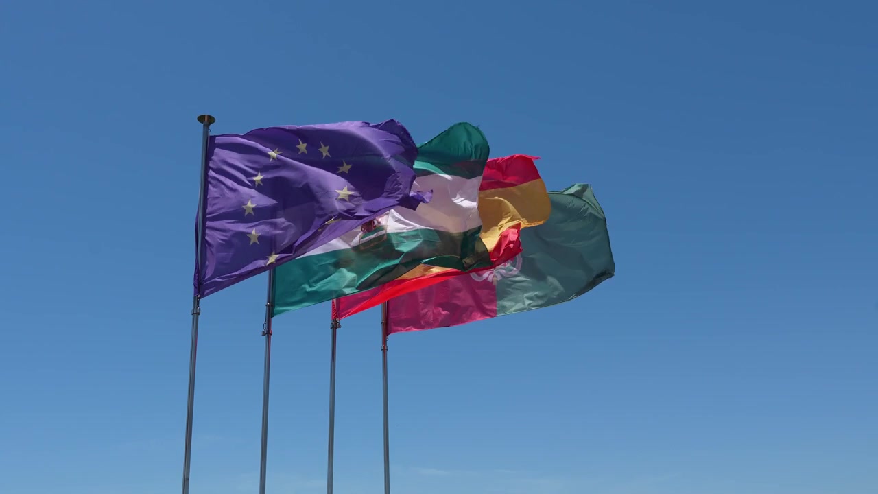 EU- og Andalusia-flagg vaier i vinden mot en klar blå himmel.