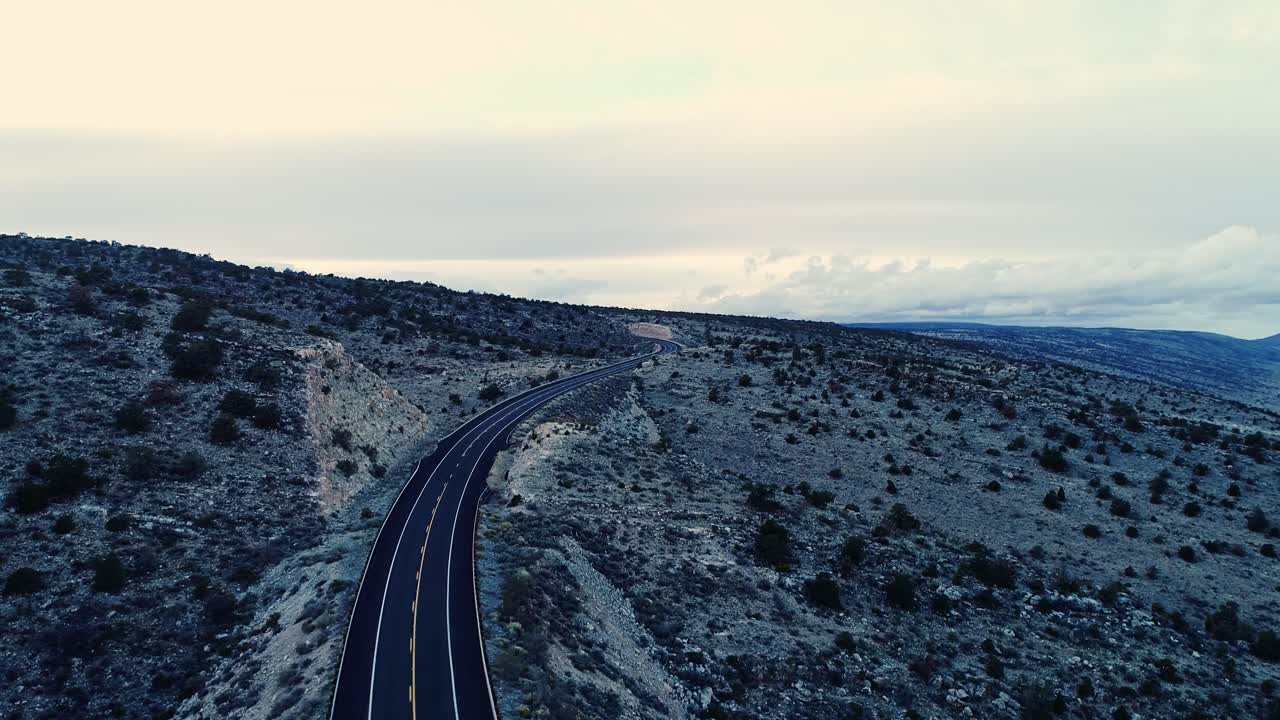 Quiet American highway through arid mountain desert with peaceful clouds above