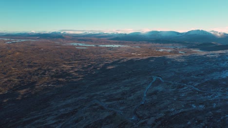 Glencoe-with-winding-river-and-mountain-range-at-dusk,-tranquil-nature-scene,-aerial-view