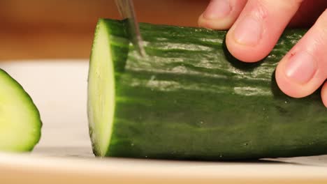 forward shot of a person slicing a cucumber with a knife