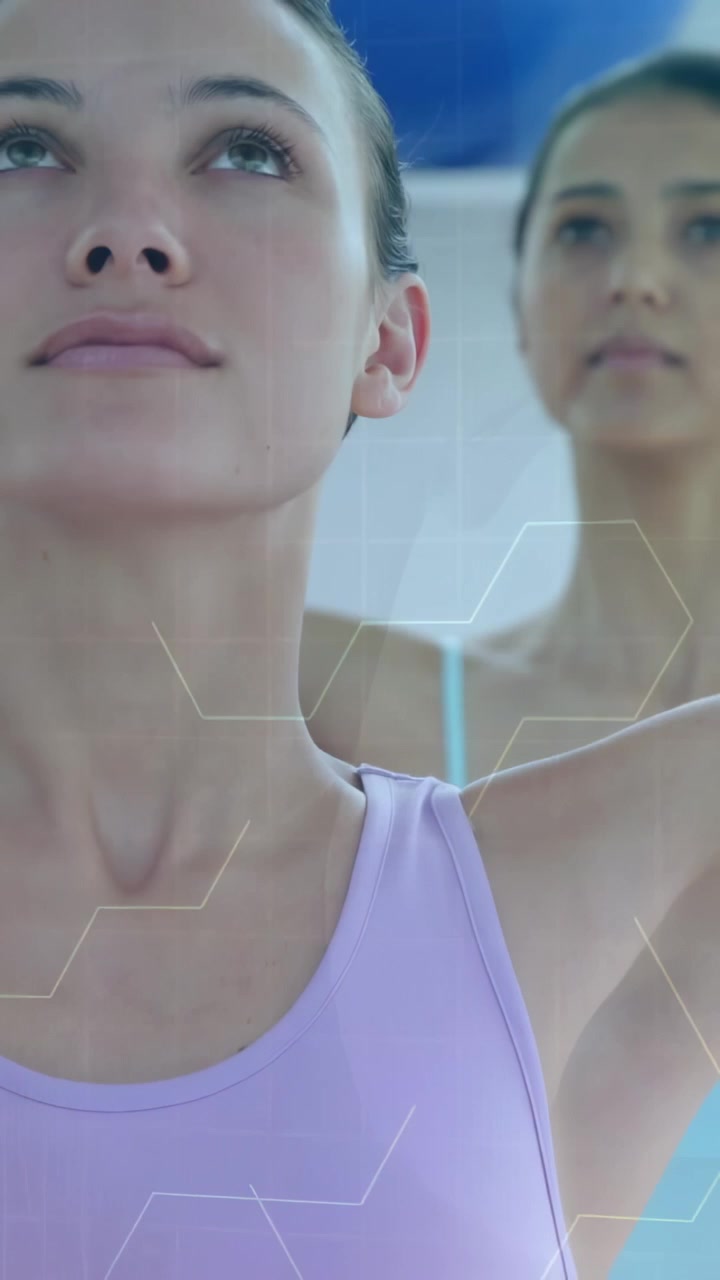 Video verticale: Istruttore che dà indicazioni alla donna in primo piano che si solleva per lo yoga, mentre una sovrapposizione esagonale si sposta sulla donna dietro che la imita.