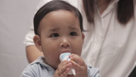 cute baby boy with chubby cheeks playing with white plastic bottle