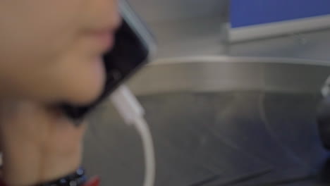 woman talking on phone in baggage claim area of the airport