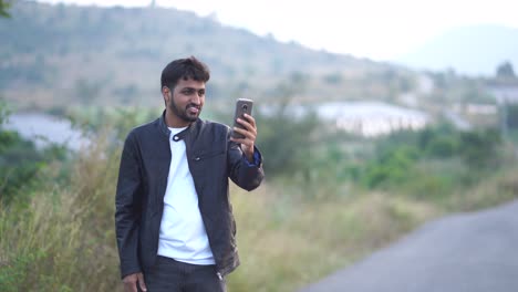 Retrato-De-Un-Niño-Sonriente-Que-Tiene-Una-Videollamada-Por-Teléfono-Móvil-Al-Aire-Libre