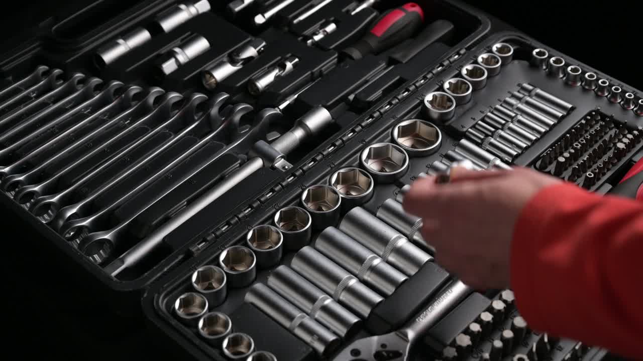 은 셔츠를 입은 남자의 가까운 손이 검은색 도구에서 도구를 선택하고 연결하고 회전하는 머리와 크롬 스패너 래 렌치