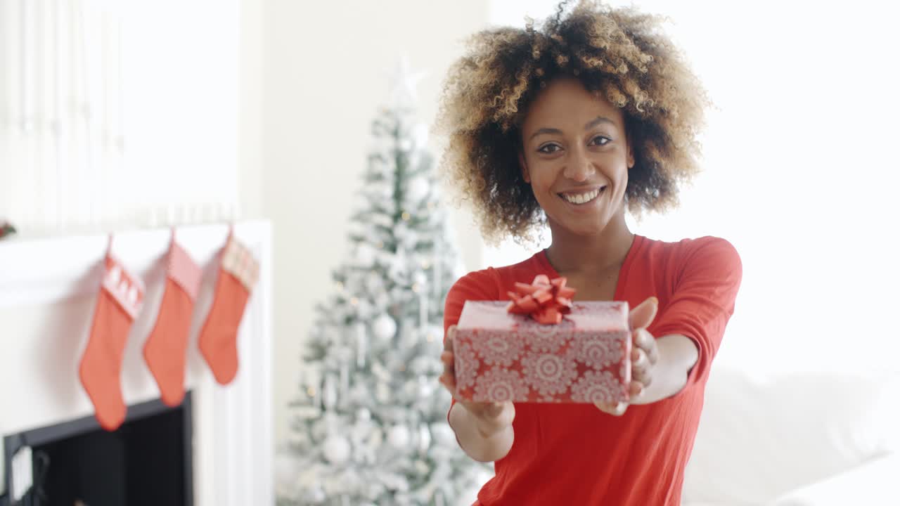 Donna africana sorridente che tiene in mano un regalo di Natale
