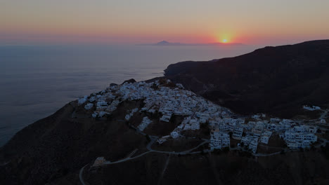 aerial panoramic overview of anafi rugged coast with white homes overlooking water at twilight, serene beauty and warm light