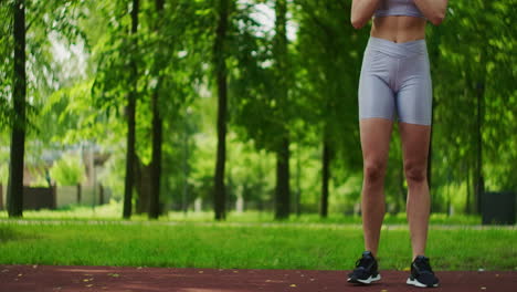 female athlete performs side lunges work out her legs in the park in slow motion. beautiful woman playing sports in the park.