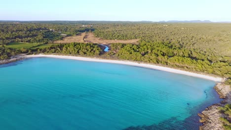 vista aérea de la playa de son saura con agua azul clara en menorca españa, seguimiento de tiro ancho