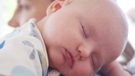 primer plano de un bebé pacífico durmiendo en el hombro de su madre