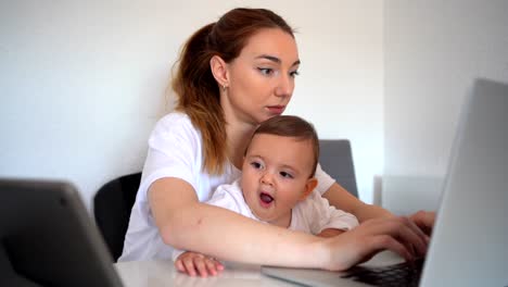 mother using laptop and baby watching cartoons on tablet