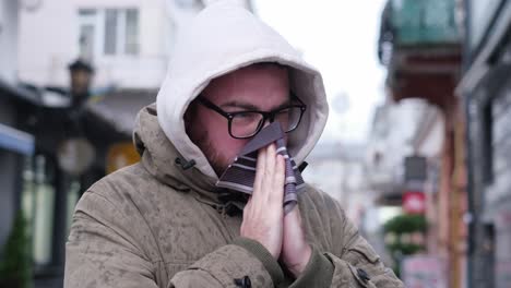 A Young Man Has a Fever in the Middle of the Street. A young man has a fever in the middle of the street. Runny nose and cold in winter. Infection with a viral disease