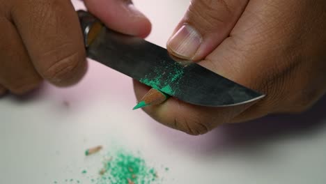 Footage-of-hands-slowly-sharpening-a-pencil-and-some-coloured-pencils-with-a-sharp-knife