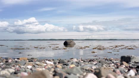 Rock-in-the-sea,-lonely-with-cloud-and-shoreline-with-gentle-waves