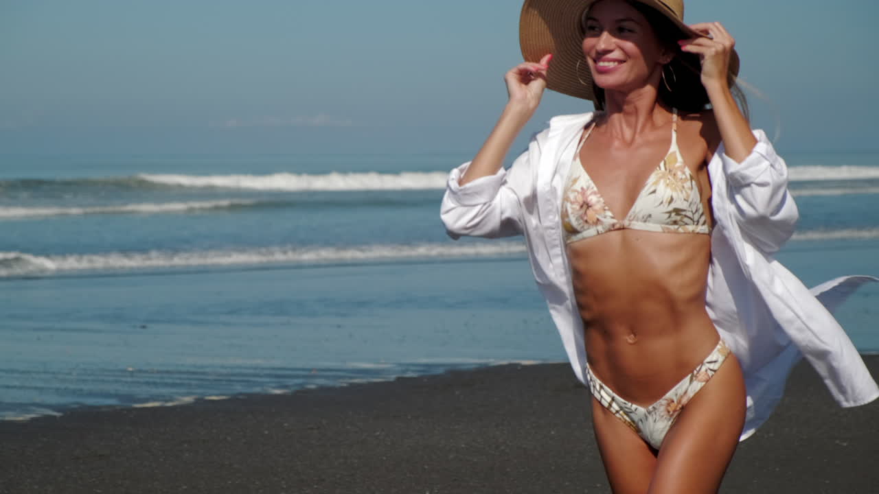 Donna in spiaggia in bikini e cappello di paglia