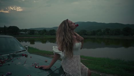 woman by vintage car at sunset by the lake