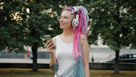 young woman listening to music and using phone outdoors