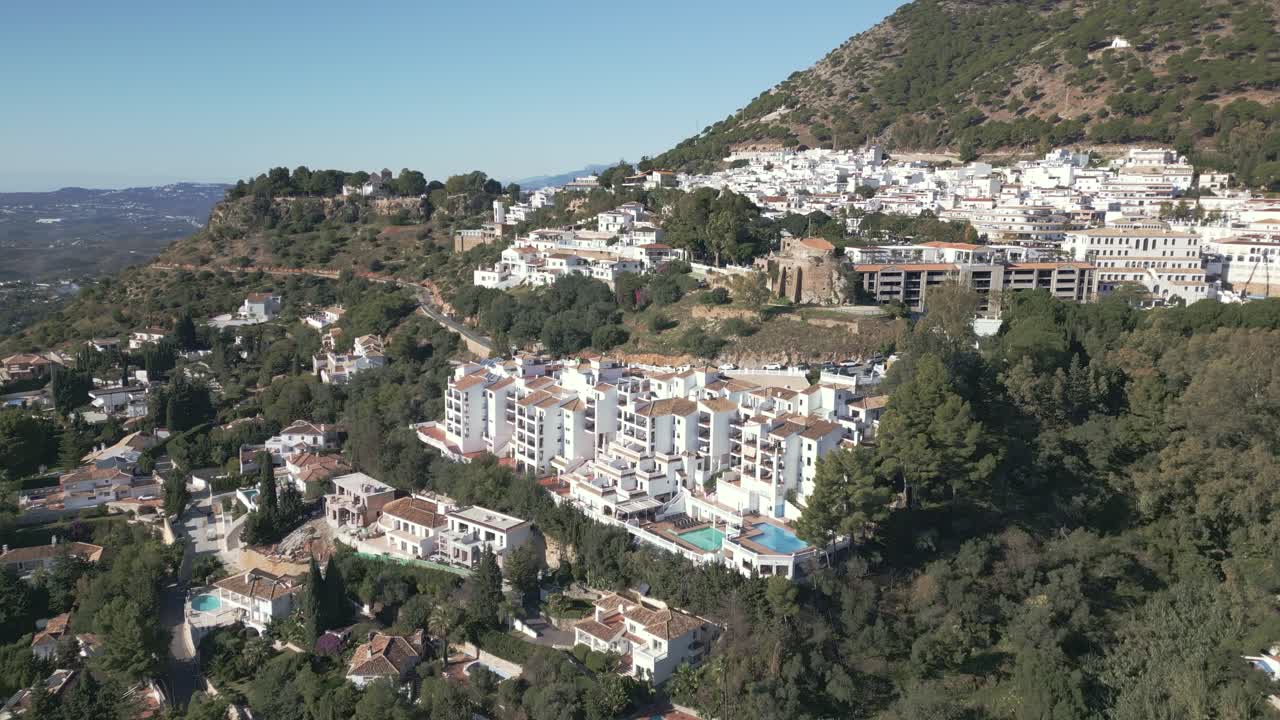 Vista aérea de Mijas, cidade costeira e montanhosa em Málaga, Espanha, que exibe a arquitetura caiada e o charme mediterrâneo sob o sol forte