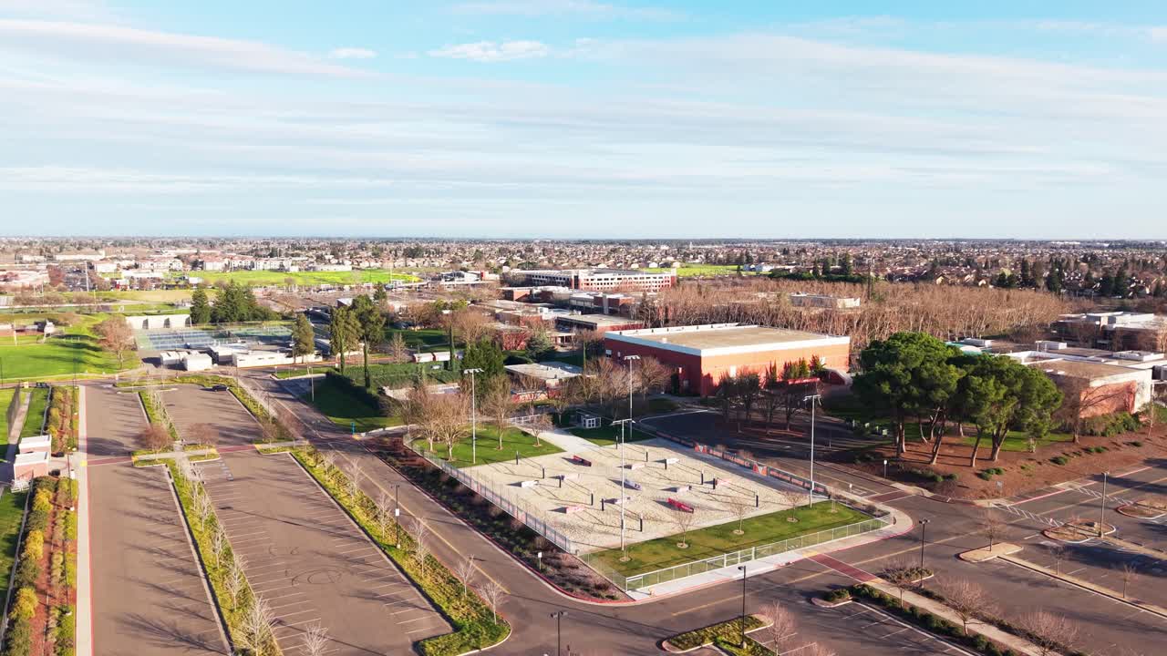 Una vista ascendente da drone mostra il Cosumnes River College con toni caldi, contrasto delicato e ampie linee visive, catturando il ritmo della vita del campus nella calma pomeridiana di Sacramento.