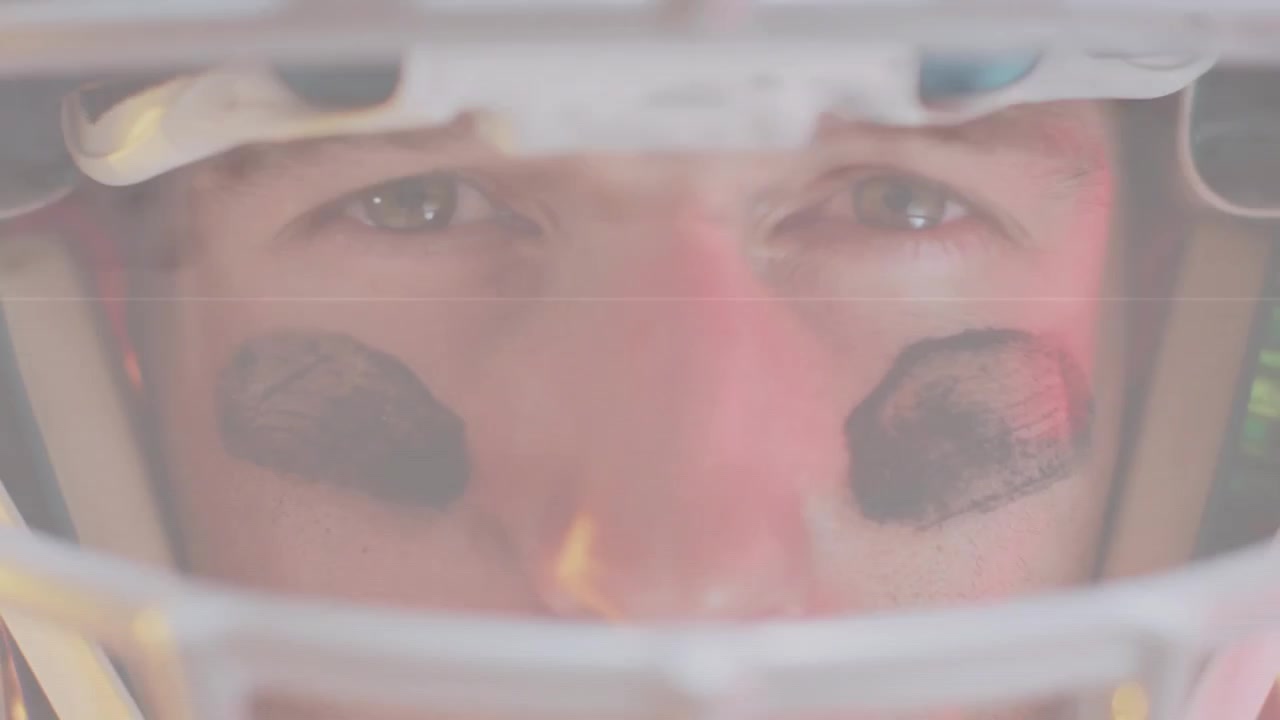 Giocatore di football americano che fissa attraverso la maschera protettiva, il riflesso della visiera provoca movimenti degli occhi, preparandosi a giocare