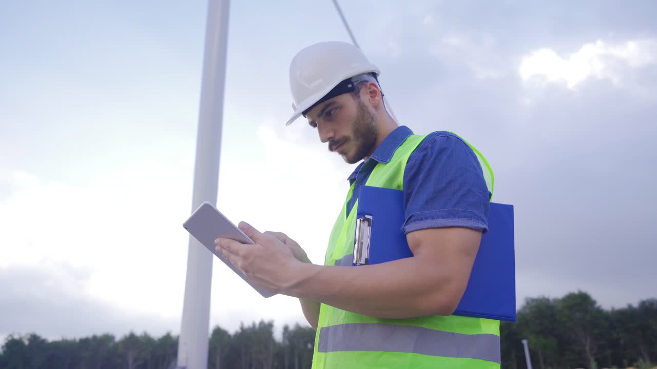 técnico ingeniero que trabaja en la turbina eólica o operador controla el viento usando una tableta.