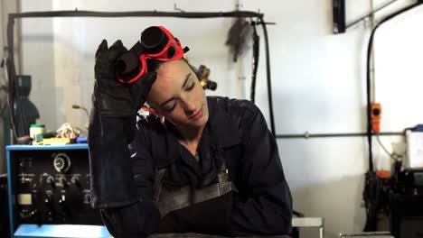 female welder leaning in workshop