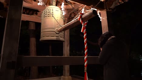 niña golpeando la campana en el santuario, tradición de año nuevo japón