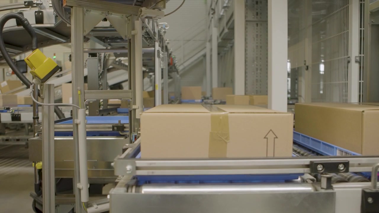 Automated conveyor belt transports cardboard boxes through modern industrial facility
