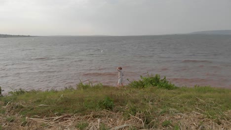 un hombre vestido con un traje de safari mirando el lago victoria en el áfrica rural
