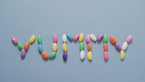 video de vista aérea de un texto delicioso formado por dulces multicolores sobre un fondo azul