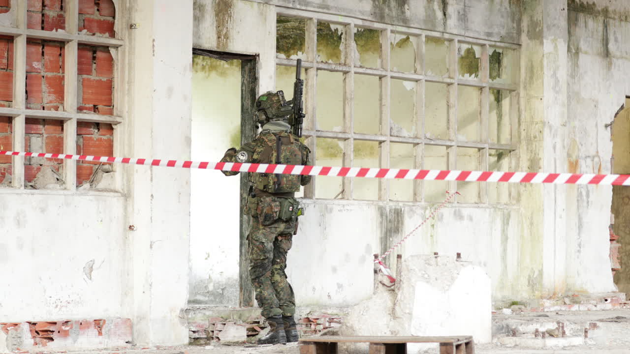 Airsoft Player On Camouflage Uniform And Holding A Rifle Gun Kicks The Door For Him To Enter
