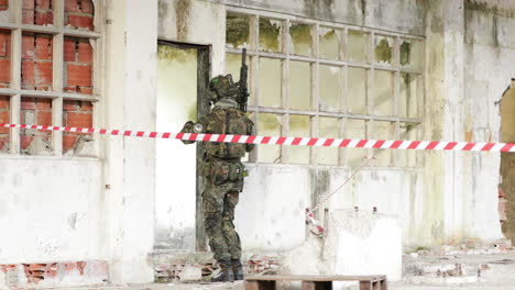 airsoft player on camouflage uniform and holding a rifle gun kicks the door for him to enter