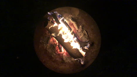 Top-down-view-of-a-fire-burning-inside-a-fire-bow,-shot-on-a-pitch-black-night