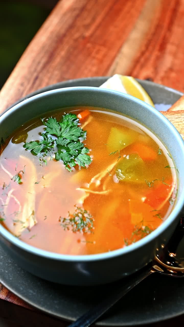 Chicken soup with vegetables and parsley in ceramic bowl. Traditional homemade chicken vegetable soup served in ceramic bowl with herbs on top