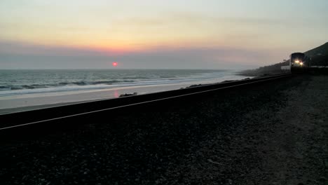 hermosa toma de un tren amtrak pasando por una playa de california al atardecer