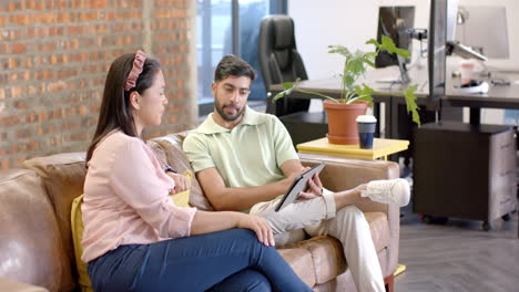 discussing work, colleagues using tablet while sitting on office couch